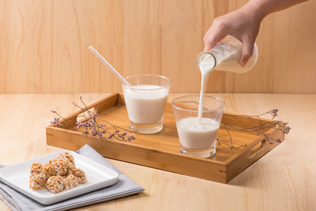 Dairy products. A bottle of milk and glass of milk serve with almond candies on a wooden table.の写真素材
