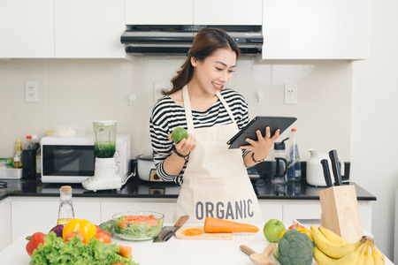 Young asian woman using a tablet computer to cook in her kitchenの写真素材