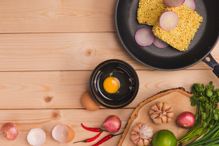 Instant noodles for cooking and eat in the dish with eggs and vegetables on wooden background.の写真素材