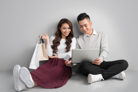 Couple shopping online. Happy couple looking together sitting floor at homeの写真素材