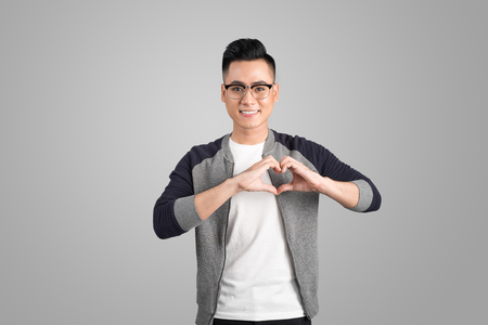 Portrait of cool handsome asian man with hands making heart shapeの写真素材