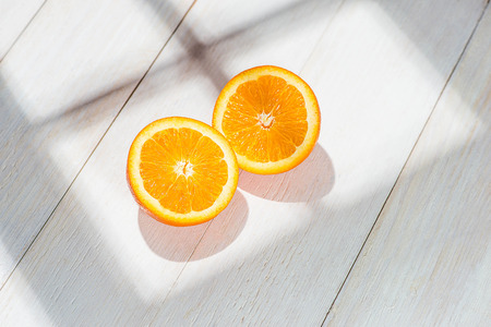 Half of orange on white wooden table.の写真素材