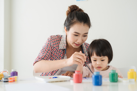 A happy family is painting. Mom help her daughter drawingの写真素材