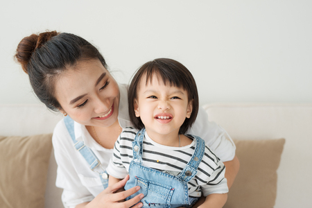 Cute little girl and her beautiful mother are happy at homeの写真素材