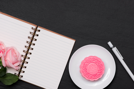 Snow skin mooncake and pink flowers on dark background. Open notebook with copy-space.の写真素材
