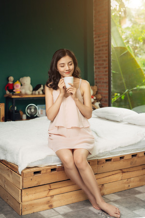 Pretty vietnamese woman enjoying her morning coffee at homeの写真素材
