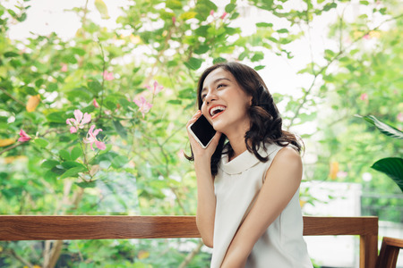 Confident young asian woman in smart casual wear talking to mobile phoneの写真素材