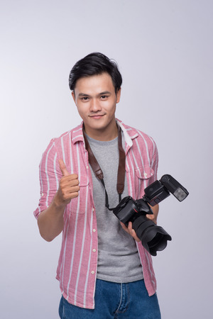 Young asian photographer holding digital camera, while working in studioの写真素材
