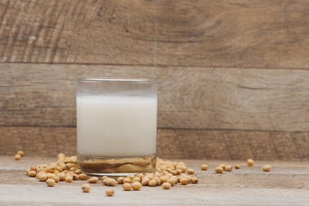 Glass with soy milk and soy bean on wooden backgroundの写真素材