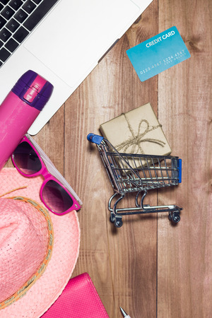 Shopping online concept. Small blue trolley and gadgets on the wooden table.の写真素材