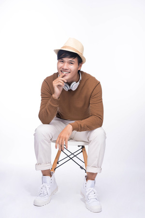 Smart casual asian man seated on chair, in studio backgroundの写真素材