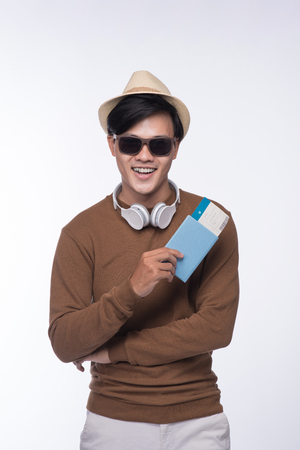 Happy asian male tourist holding passport over grey backgroundの写真素材
