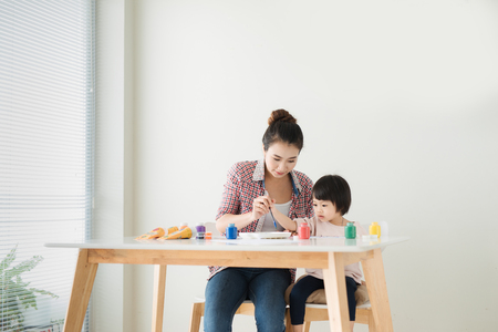 Happy family mother and daughter together paint. Asian woman helps her child girl.の写真素材
