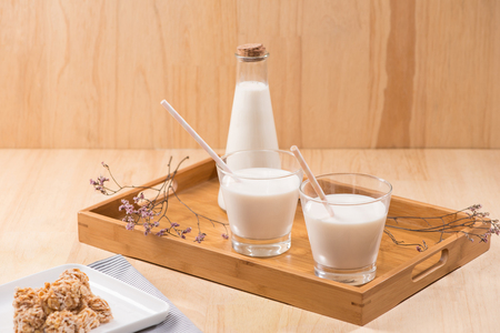 Dairy products. A bottle of milk and glass of milk serve with almond candies on a wooden table.の写真素材