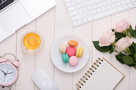 White desk with colorful macaroons, keyboard and open notebook.の写真素材