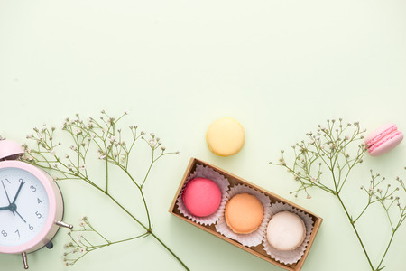 French macaroons. Many variegated sweet macarons in box with bouquet of pink roses on the tableの写真素材