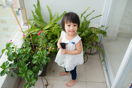 Child taking care of plants. Cute little girl watering first spring flowersの写真素材