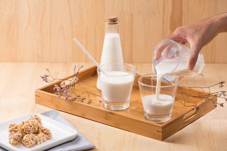 Dairy products. A bottle of milk and glass of milk serve with almond candies on a wooden table.の写真素材