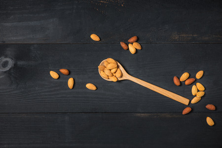 Almonds in spoon on wooden table. Almond nuts.の写真素材