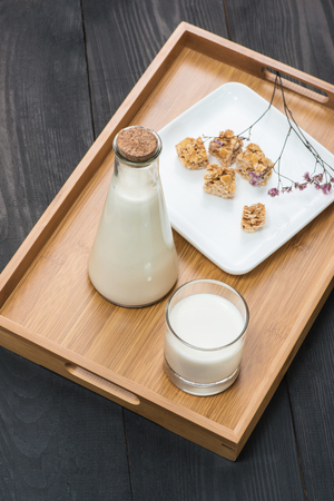 Dairy products. A bottle of milk and glass of milk serve with almond candies on a rustic wooden table.の写真素材