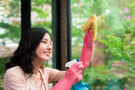 Smiling young asian woman housewife washes a windowの写真素材