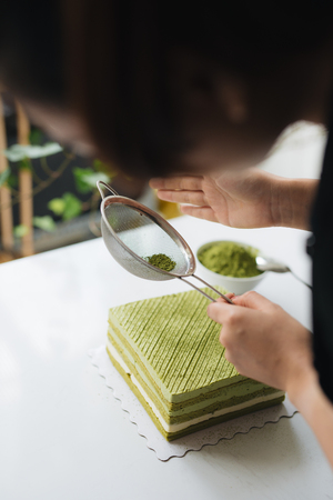 Pour green tea powder over delicious cheesecakeの写真素材