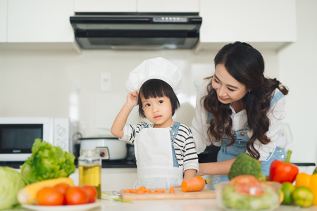 Mother with her daughter in the kitchen cooking togetherの写真素材