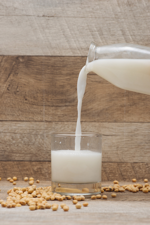 Glass with soy milk and soy bean on wooden backgroundの写真素材