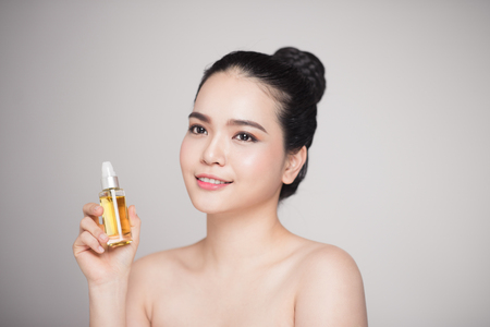Beauty concept. Asian pretty woman with perfect skin holding oil bottleの写真素材
