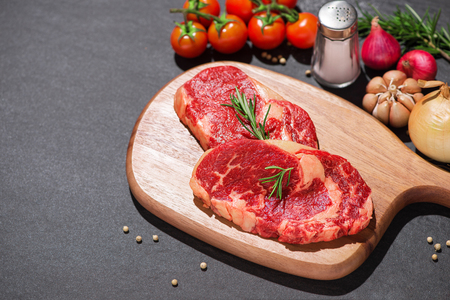 Raw beef on a cutting board  with spices and ingredients for cooking.の写真素材