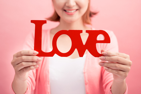 Pretty asian young woman holding wooden letters LOVE on link background.の写真素材