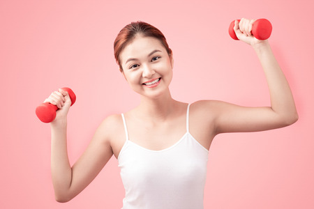 Woman Lifting Weights. Fitness woman lifting weights smiling happy on pink background.の写真素材