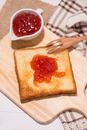 Toast with strawberry jam on a plate on table.の写真素材