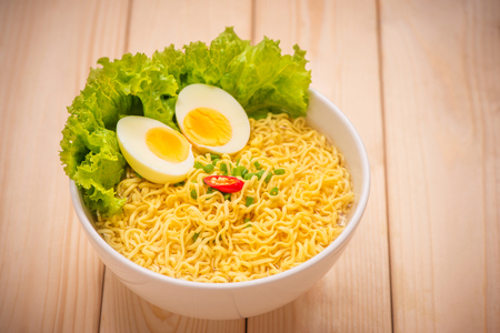 Instant noodles in bowl with vegetables and  boiled egg on wood backgroundの写真素材