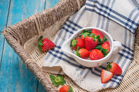 Bowl with fresh strawberry on blue wooden table.の写真素材