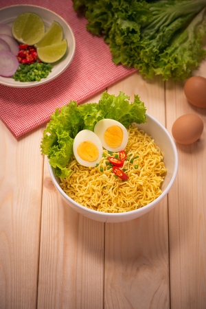 Instant noodles in bowl with vegetables and  boiled egg on wood backgroundの写真素材