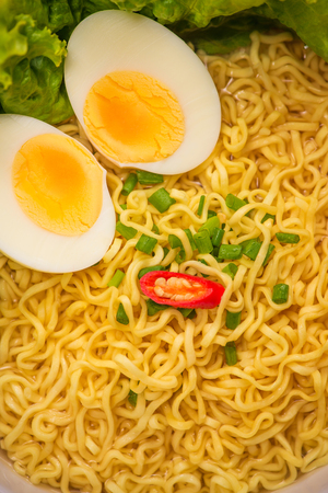 Instant noodles in bowl with vegetables and  boiled egg on wood backgroundの写真素材