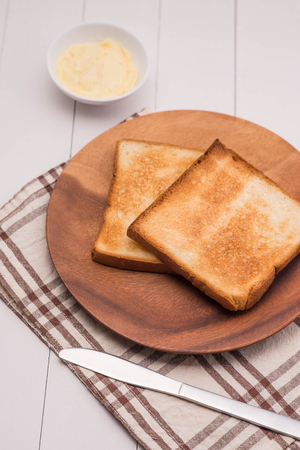 Close-up of slice of toast bread with butter on wood tableの写真素材