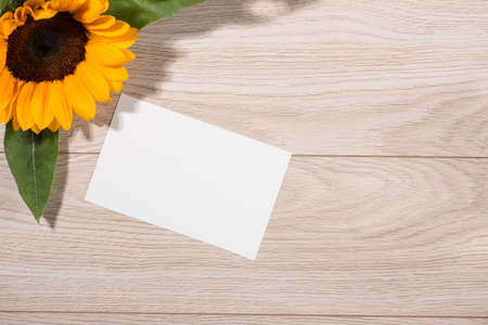 Yellow flowers and empty paper for your text on wooden backgroundの写真素材