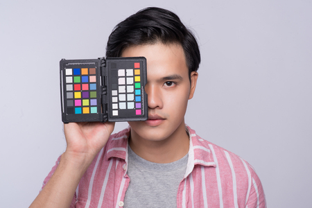 Young asian photographer holding digital camera, while working in studioの写真素材