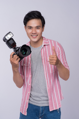 Young asian photographer holding digital camera, while working in studioの写真素材