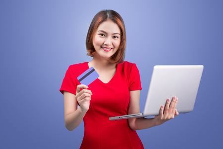 Online shopping. Asian woman holding laptop and credit card ready to pay.の写真素材