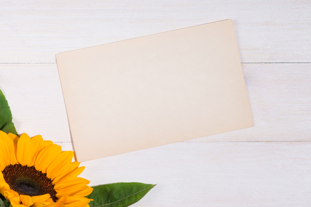Yellow flowers and empty paper for your text on wooden backgroundの写真素材
