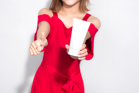 Beautiful asian woman standing red dress and holding cosmetic product.の写真素材