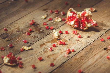 Falling down ripe pomegranate with cracks and splashes of juice and seeds wooden vintage background.の写真素材