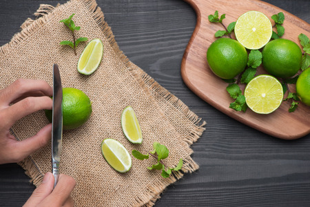 Fresh limes on cutting board on wooden table. Top view, background.の写真素材