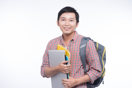 Portrait of young asian student holding books and laptopの写真素材