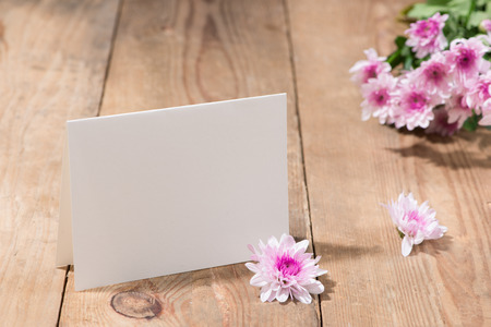 Pink flowers and empty paper for your text on wooden backgroundの写真素材