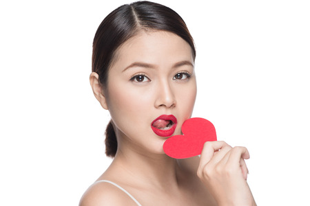 Attractive young asian woman holding red heart. Valentine's day art portrait. Perfect make upの写真素材