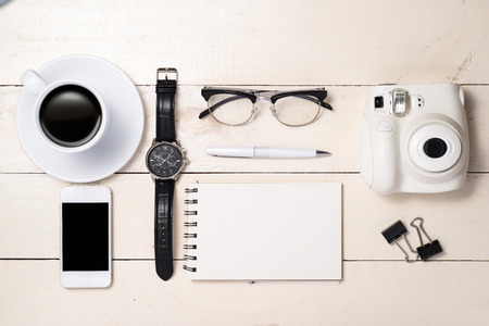 Office desk. Pen, eyeglasses, coffee, camera, smartphone, watch and notebook on table. Top view.の写真素材